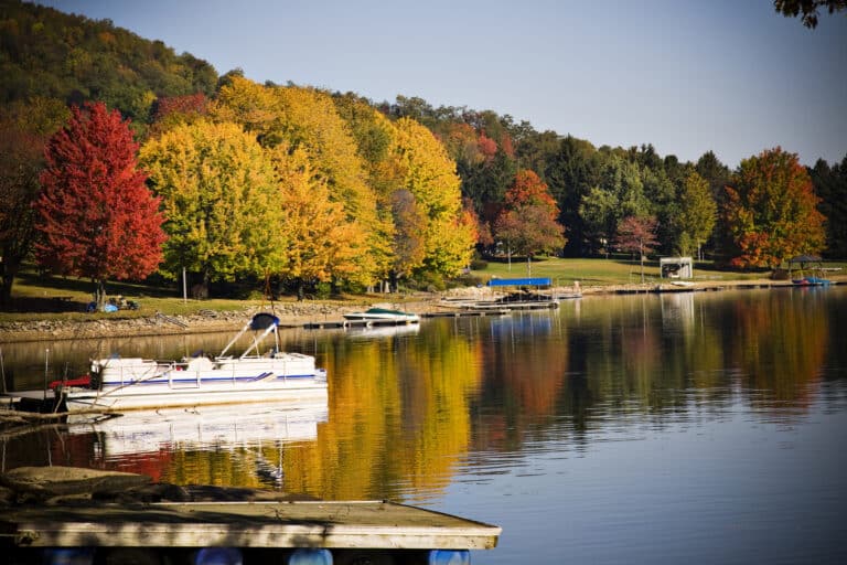 Boat in Deep Creek Lake and vibrant fall foliage. Autumn is the best time to visit Deep Creek Lake if you love leaf peeing.
